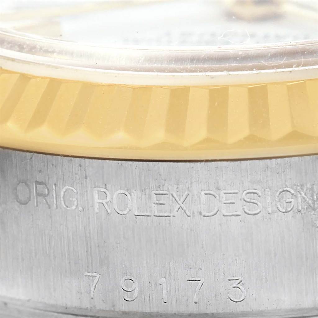 The image shows a close-up of the side of a Rolex Datejust 79173 Women's Steel and Gold (two tone) White Dial 79173 Women's Steel and Gold (two tone) White Dial watch, highlighting the bezel and engraved serial number.