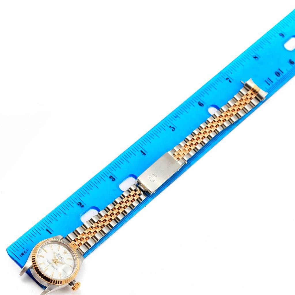 The image shows a Rolex Datejust 79173 Women's Steel and Gold (two tone) White Dial 79173 Women's Steel and Gold (two tone) White Dial watch laid flat next to a blue ruler, displaying the face and bracelet.