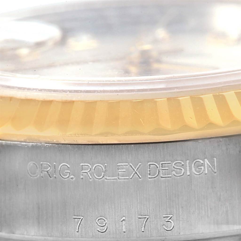 This close-up of a Rolex Datejust 79173 Women's Stainless Steel Silver Dial 79173 Women's Stainless Steel Silver Dial watch shows the bottom part of the bezel and case, featuring text engraving and the model number 79173.