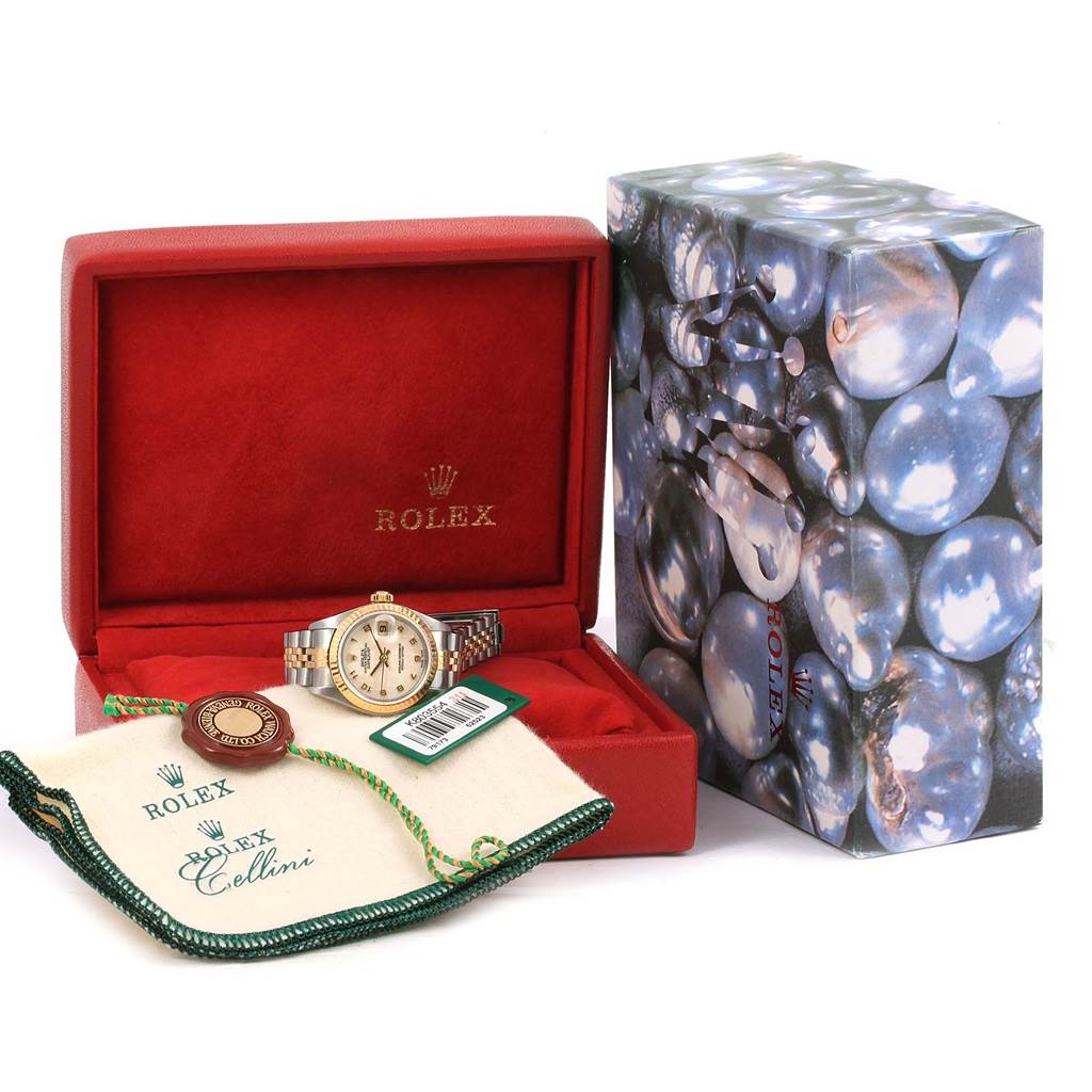 The Rolex Datejust 79173 Women's Steel and Gold (two tone) Beige Dial 79173 Women's Steel and Gold (two tone) Beige Dial watch is shown from a front angle, housed in an open red case with additional accessories and tags displayed.