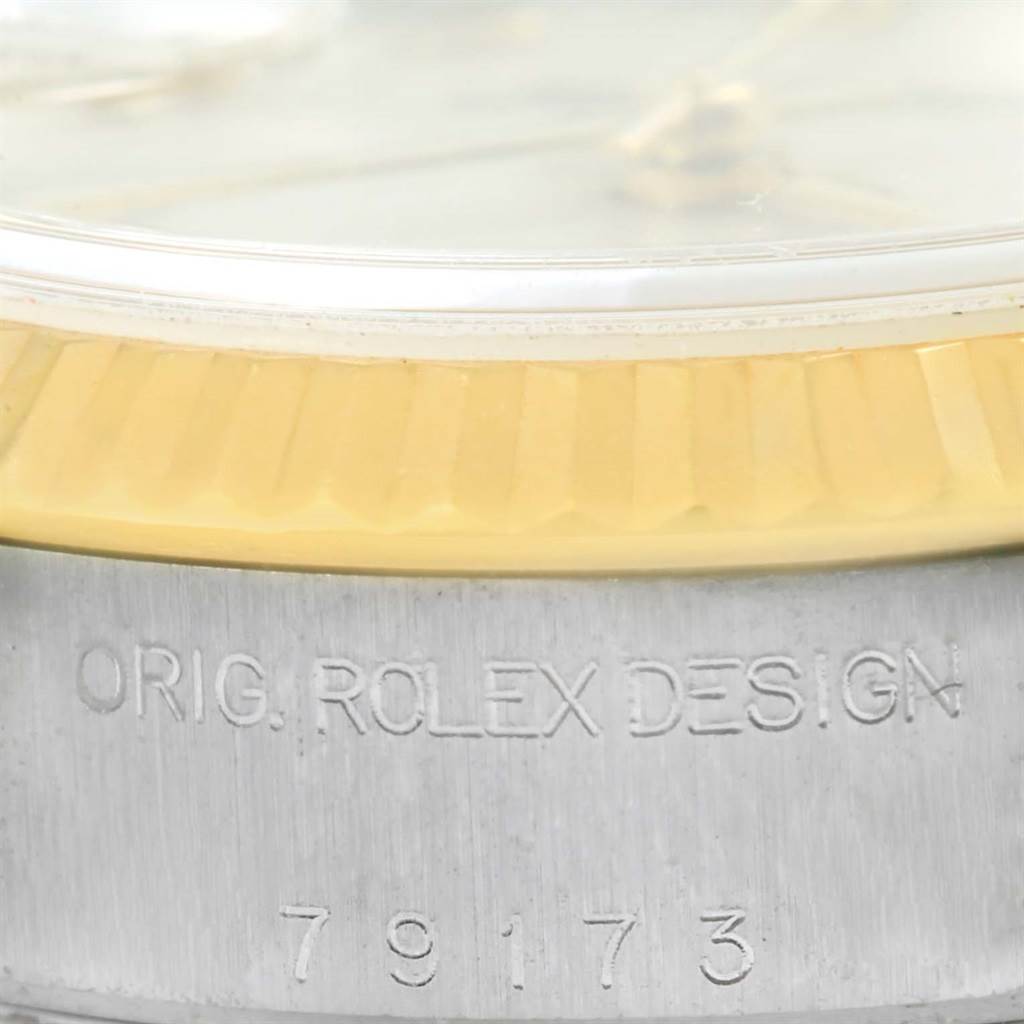 The image shows a side angle of the Rolex Datejust 79173 Women's Steel and Gold (two tone) Beige Dial 79173 Women's Steel and Gold (two tone) Beige Dial model, focusing on the bezel and the serial number engraving.