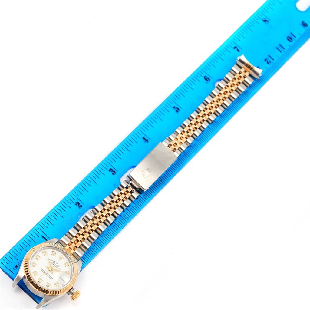 The Rolex Datejust 69173 Women's Stainless Steel White Dial 69173 Women's Stainless Steel White Dial watch is shown from above, with its face, crown, bracelet, and clasp visible next to a blue ruler.