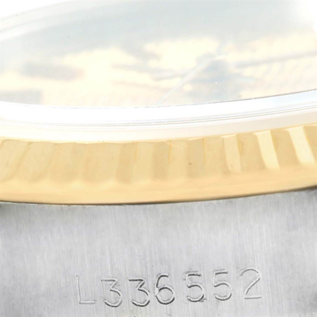 The image shows a close-up of the Rolex Datejust 69173 Women's Stainless Steel Champagne Dial 69173 Women's Stainless Steel Champagne Dial watch's fluted bezel and part of its serial number engraving on the case.
