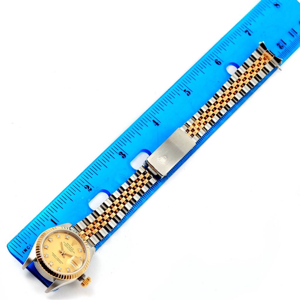 This image shows a Rolex Datejust 69173 Women's Stainless Steel Champagne Dial 69173 Women's Stainless Steel Champagne Dial watch from an overhead angle, with its band extended alongside a blue ruler for measurement.