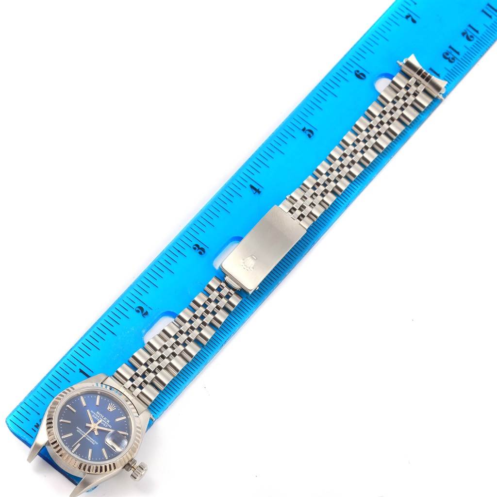 The image shows the Rolex Datejust 69174 Women's Stainless Steel Blue Dial 69174 Women's Stainless Steel Blue Dial watch laid flat with a blue ruler beside it, highlighting the face and bracelet.