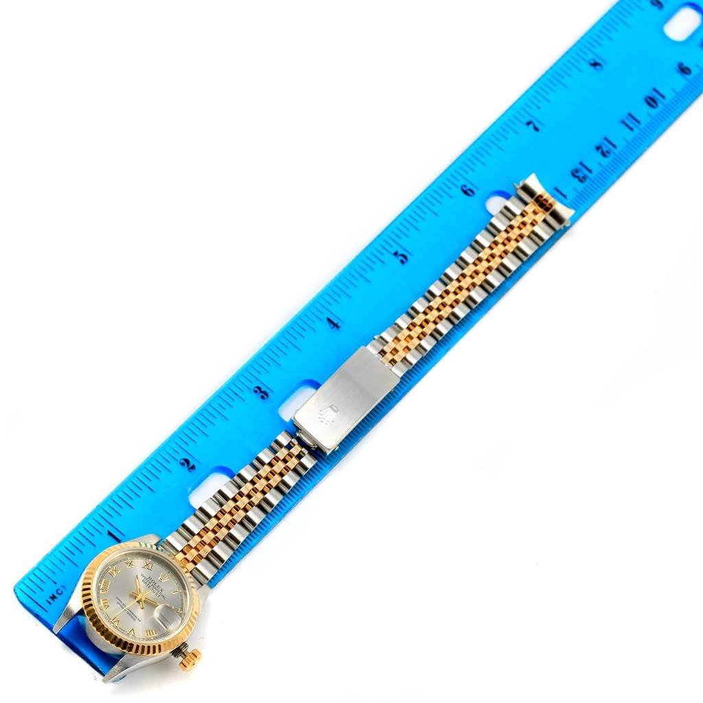 This image shows the entire Rolex Datejust 69173 Women's Stainless Steel Grey Dial 69173 Women's Stainless Steel Grey Dial watch, laid flat, with a blue ruler alongside it.