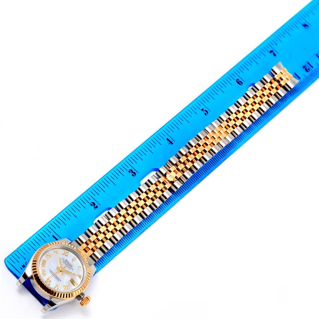 The image shows a top-down view of a Rolex Datejust 179173 Women's Steel and Gold (two tone) Mother of Pearl Dial 179173 Women's Steel and Gold (two tone) Mother of Pearl Dial watch and its band, positioned alongside a ruler.