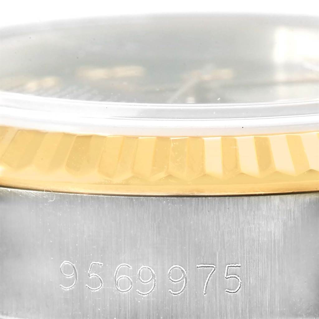 This image shows a close-up of the Rolex Datejust 69173 Women's Stainless Steel Grey Dial 69173 Women's Stainless Steel Grey Dial watch's bezel, crystal, and part of the case with a serial number.