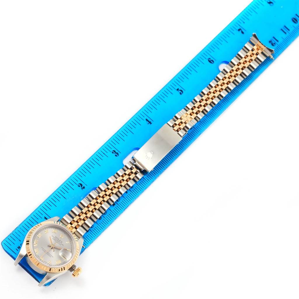 The Rolex Datejust 69173 Women's Stainless Steel Grey Dial 69173 Women's Stainless Steel Grey Dial watch is shown from a top view, highlighting its face and band alongside a blue ruler for size reference.