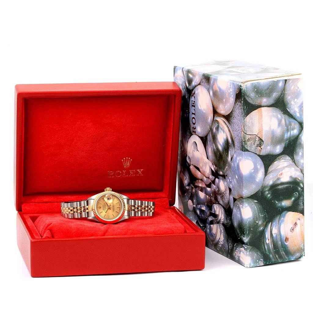 The Rolex Datejust 69173 Women's Stainless Steel Champagne Dial 69173 Women's Stainless Steel Champagne Dial watch is shown front-facing in an open red box, with its packaging to the right.