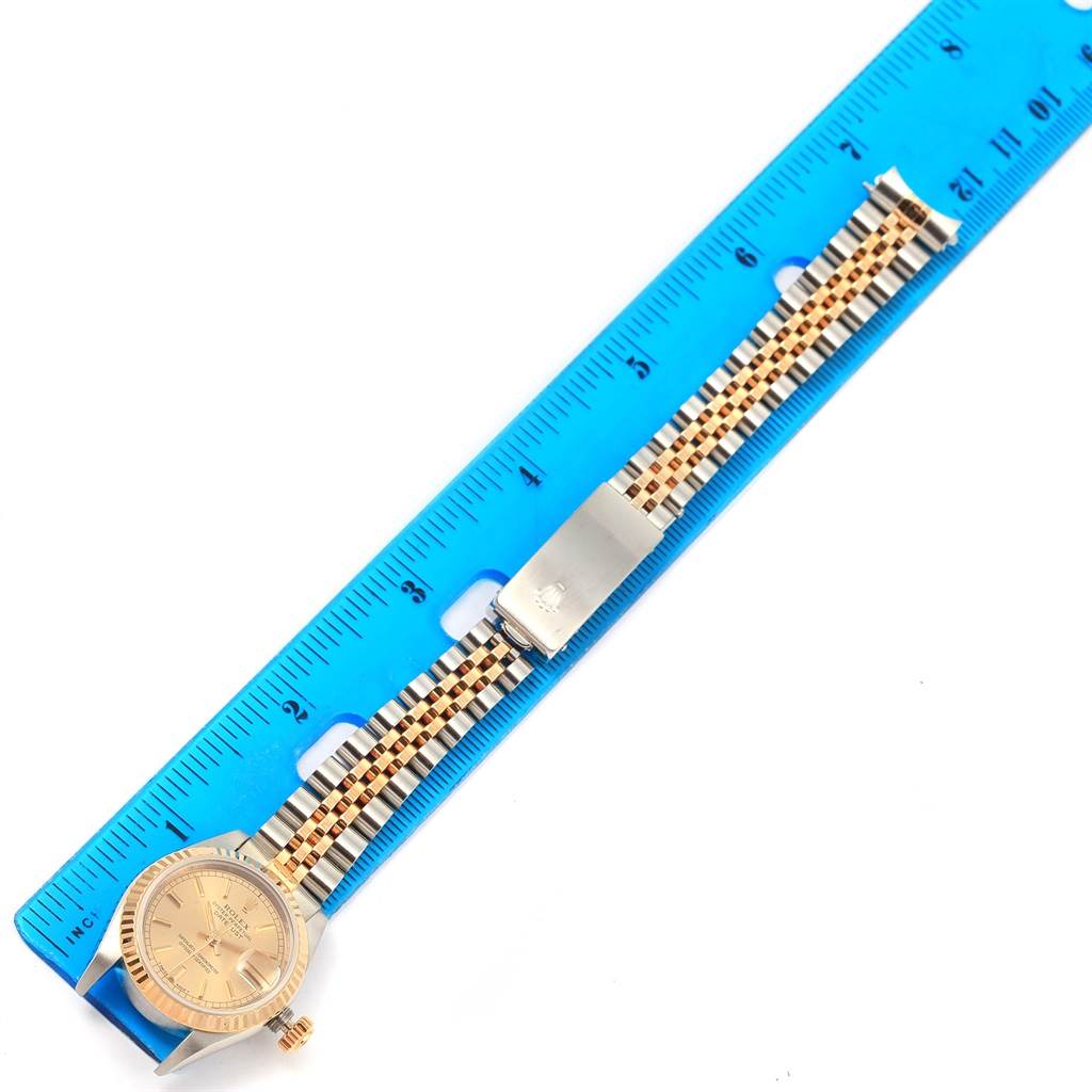 The image shows a top-down view of a Rolex Datejust 69173 Women's Stainless Steel Champagne Dial 69173 Women's Stainless Steel Champagne Dial watch resting on a ruler, highlighting its face, bezel, and bracelet.