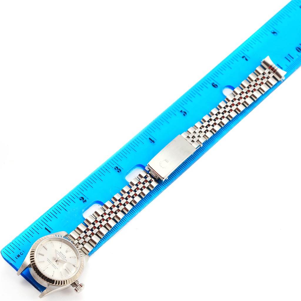 The image shows a Rolex Datejust 79174 Women
s Stainless Steel Silver Dial 79174 Women
s Stainless Steel Silver Dial watch laid flat with its bracelet extended next to a blue ruler for measurement.