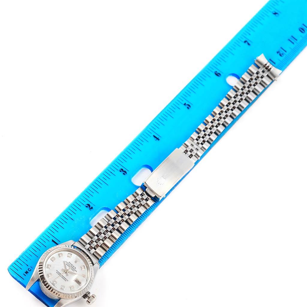 The image shows the Rolex Datejust 79174 Women's Stainless Steel Mother of Pearl Dial 79174 Women's Stainless Steel Mother of Pearl Dial watch placed against a ruler, displaying its face, bezel, and bracelet.