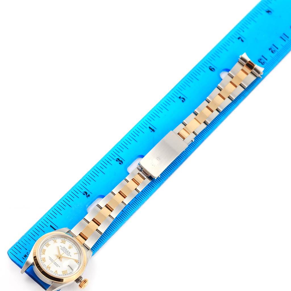 The Rolex Datejust 79163 Women's Steel and Gold (two tone) White Dial 79163 Women's Steel and Gold (two tone) White Dial watch is shown flat with its face and bracelet alongside a blue ruler for size reference.