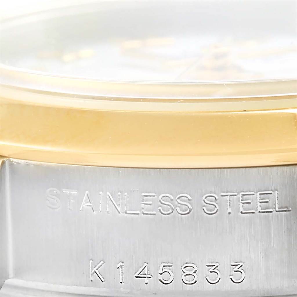 The image shows a close-up of the side of a Rolex Datejust 79163 Women's Steel and Gold (two tone) White Dial 79163 Women's Steel and Gold (two tone) White Dial watch, focusing on the stainless steel case with an engraved serial number.