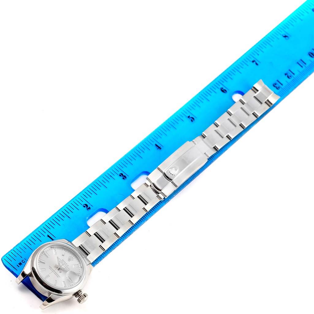 This image shows a Rolex Datejust 179160 Women's Stainless Steel Silver Dial 179160 Women's Stainless Steel Silver Dial watch laying flat with its bracelet extended next to a blue ruler for scale.