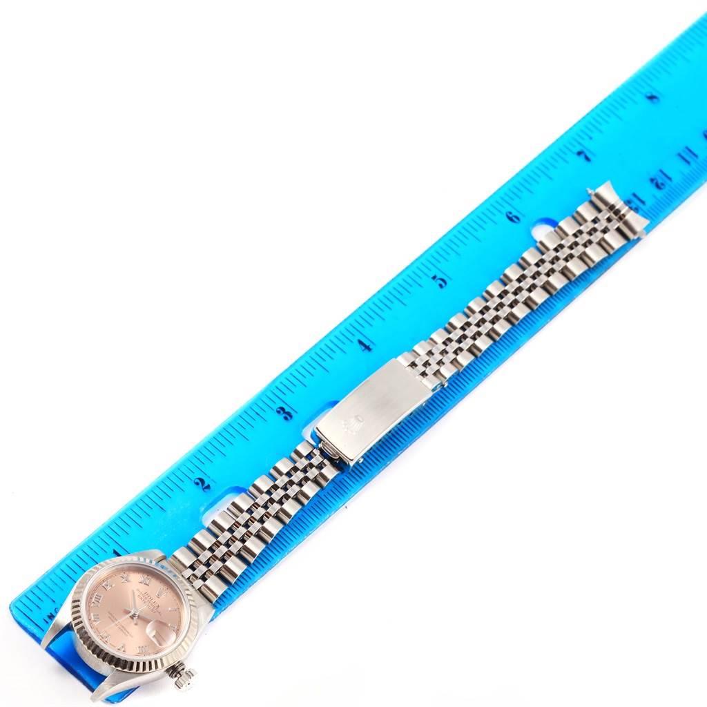 The Rolex Datejust 69174 Women's Stainless Steel Pink Dial 69174 Women's Stainless Steel Pink Dial watch is shown in a top-down view, with a focus on the dial, bracelet, and clasp, next to a ruler for size reference.