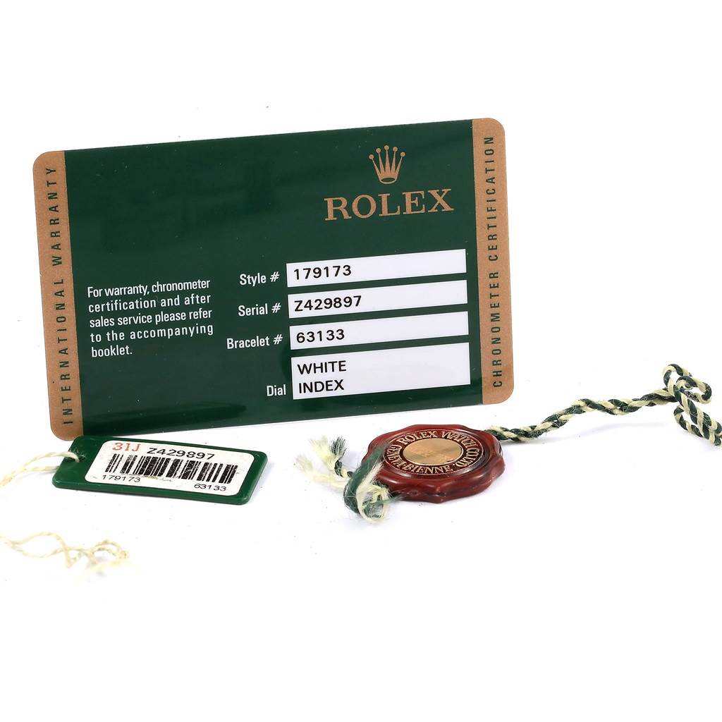 This image shows a Rolex Datejust 179173 Women's Steel and Gold (two tone) White Dial 179173 Women's Steel and Gold (two tone) White Dial warranty card, a green serial tag, and a red wax Rolex certification seal.