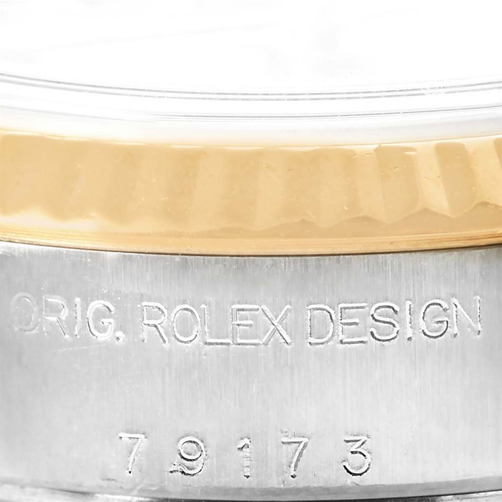This image shows a close-up of the case side of a Rolex Datejust 79173 Women's Stainless Steel Silver Dial 79173 Women's Stainless Steel Silver Dial watch with engraved text and a glimpse of the bezel.