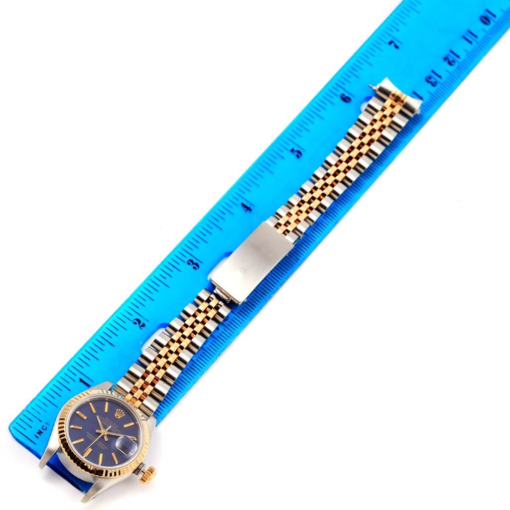 The image shows a Rolex Datejust 69173 Women's Stainless Steel Blue Dial 69173 Women's Stainless Steel Blue Dial watch with a jubilee bracelet laid on a blue ruler for measurement.