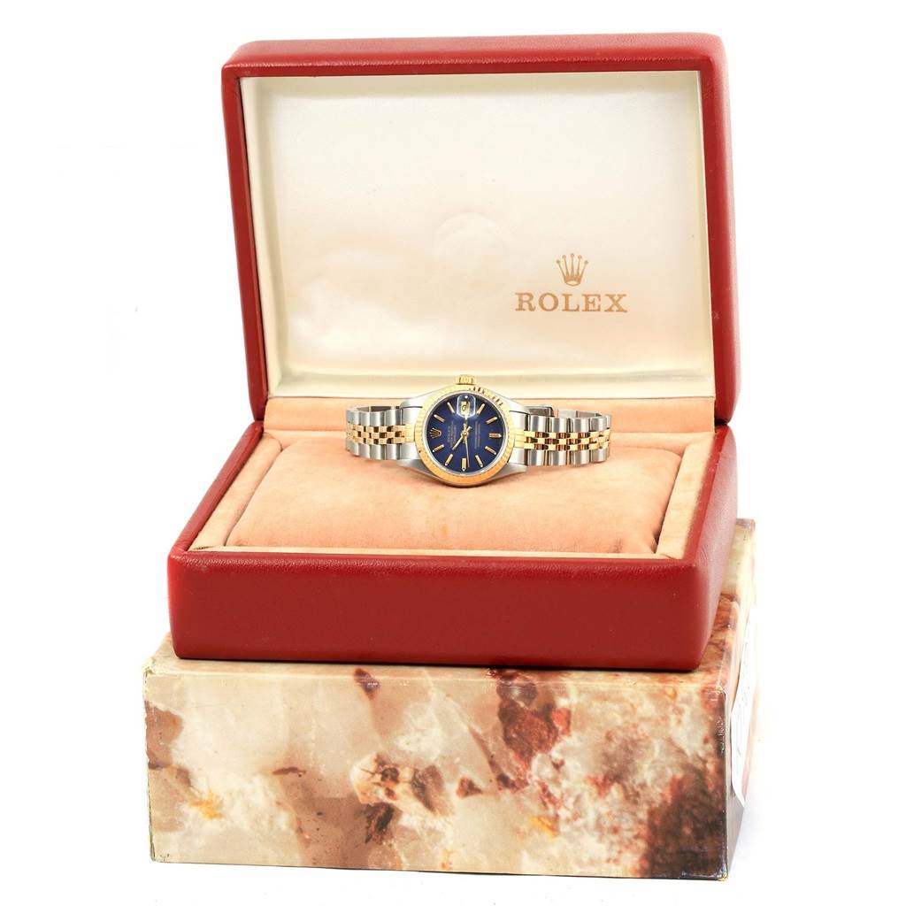 The Rolex Datejust 69173 Women's Stainless Steel Blue Dial 69173 Women's Stainless Steel Blue Dial watch is displayed front-facing, inside an open red and white box on a marble-patterned base.