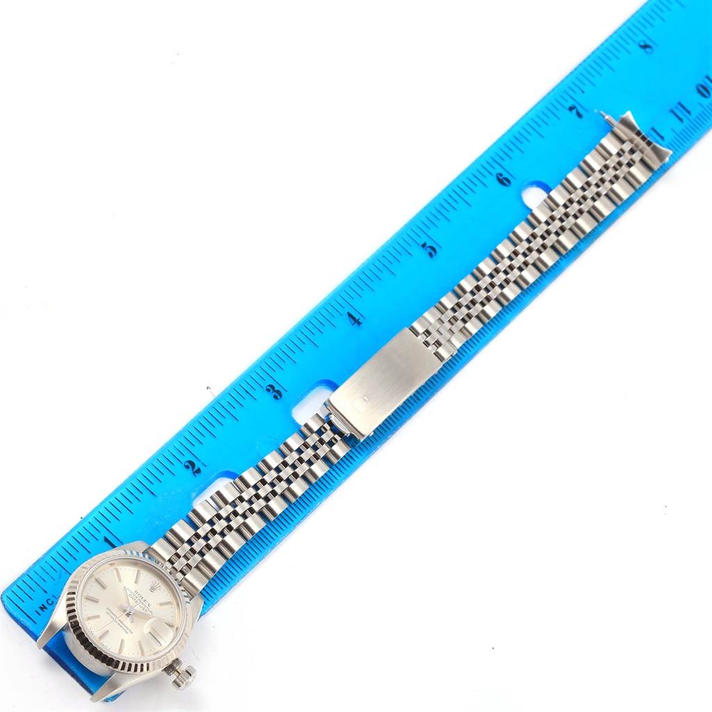 The image shows a Rolex Datejust 69174 Women's Stainless Steel Silver Dial 69174 Women's Stainless Steel Silver Dial watch laid flat with its bracelet extended beside a blue ruler for measurement.