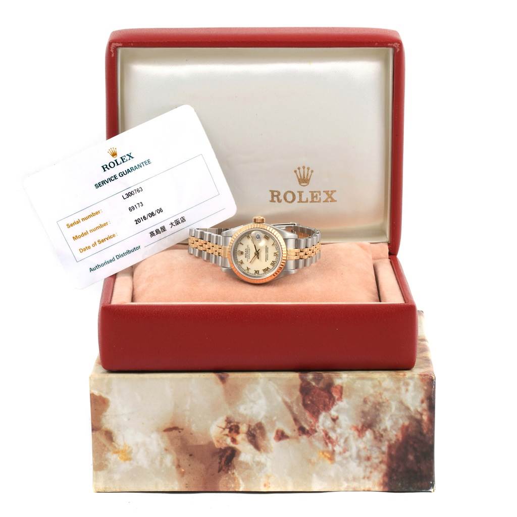 The Rolex Datejust 69173 Women's Stainless Steel Beige Dial 69173 Women's Stainless Steel Beige Dial watch is displayed front-on in its box, with a service guarantee card beside it.