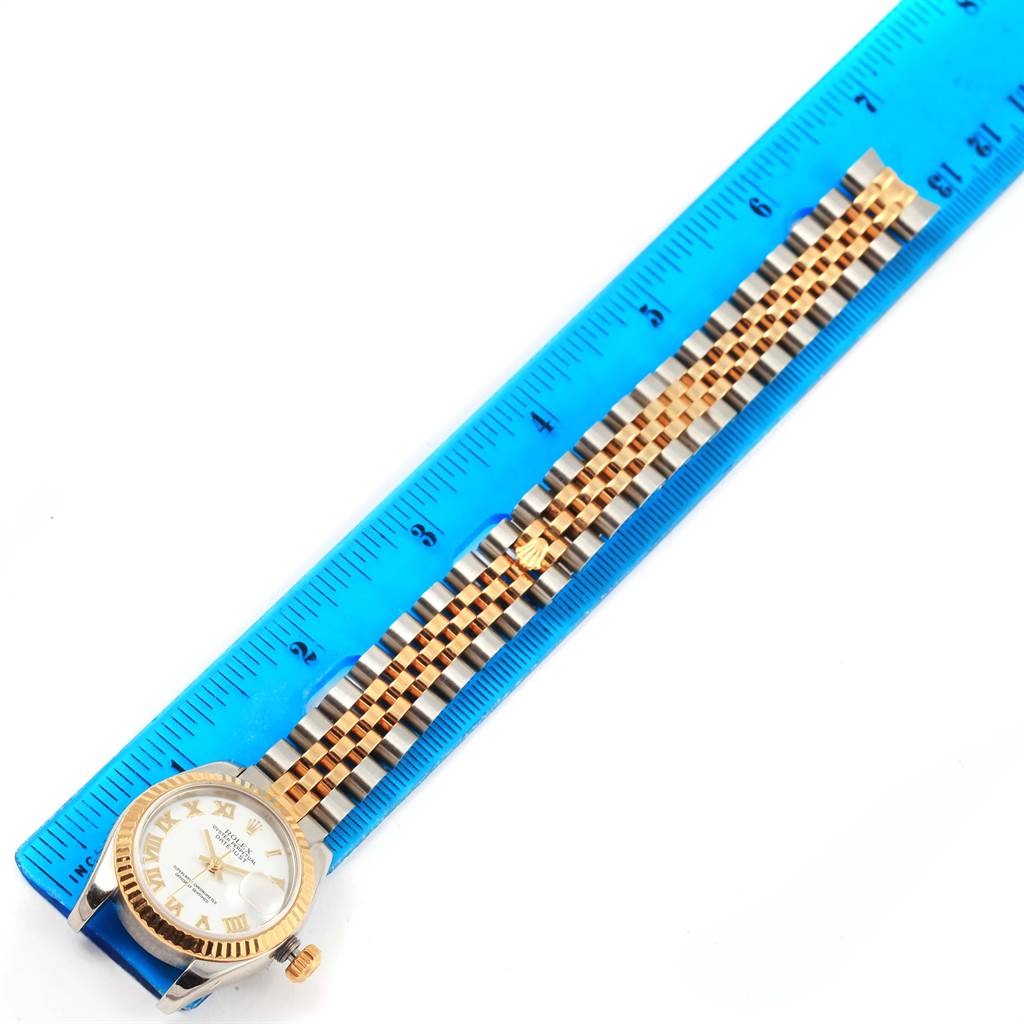 The image shows a Rolex Datejust 179173 Women's Steel and Gold (two tone) White Dial 179173 Women's Steel and Gold (two tone) White Dial watch laid next to a ruler, displaying the watch's face and bracelet.