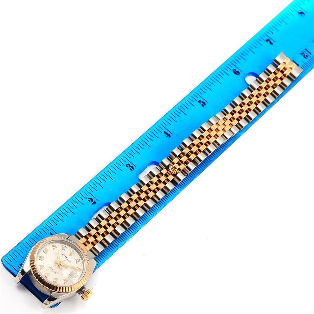 The Rolex Datejust 179173 Women's Steel and Gold (two tone) Silver Dial 179173 Women's Steel and Gold (two tone) Silver Dial watch is shown in a top-down view alongside a blue ruler for scale.