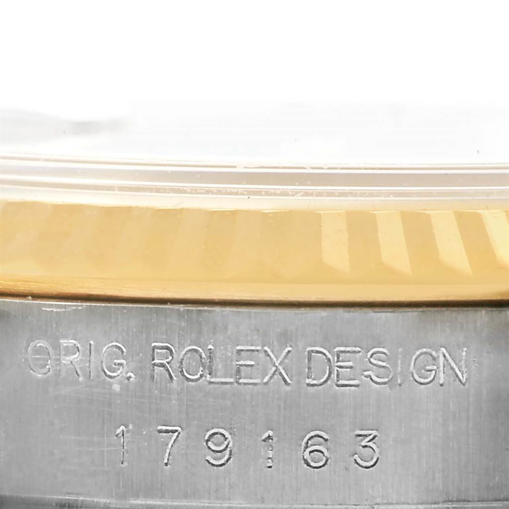 This close-up of the Rolex Datejust 179173 Women's Steel and Gold (two tone) Silver Dial 179173 Women's Steel and Gold (two tone) Silver Dial shows the engraved serial number and part of the fluted bezel and case.