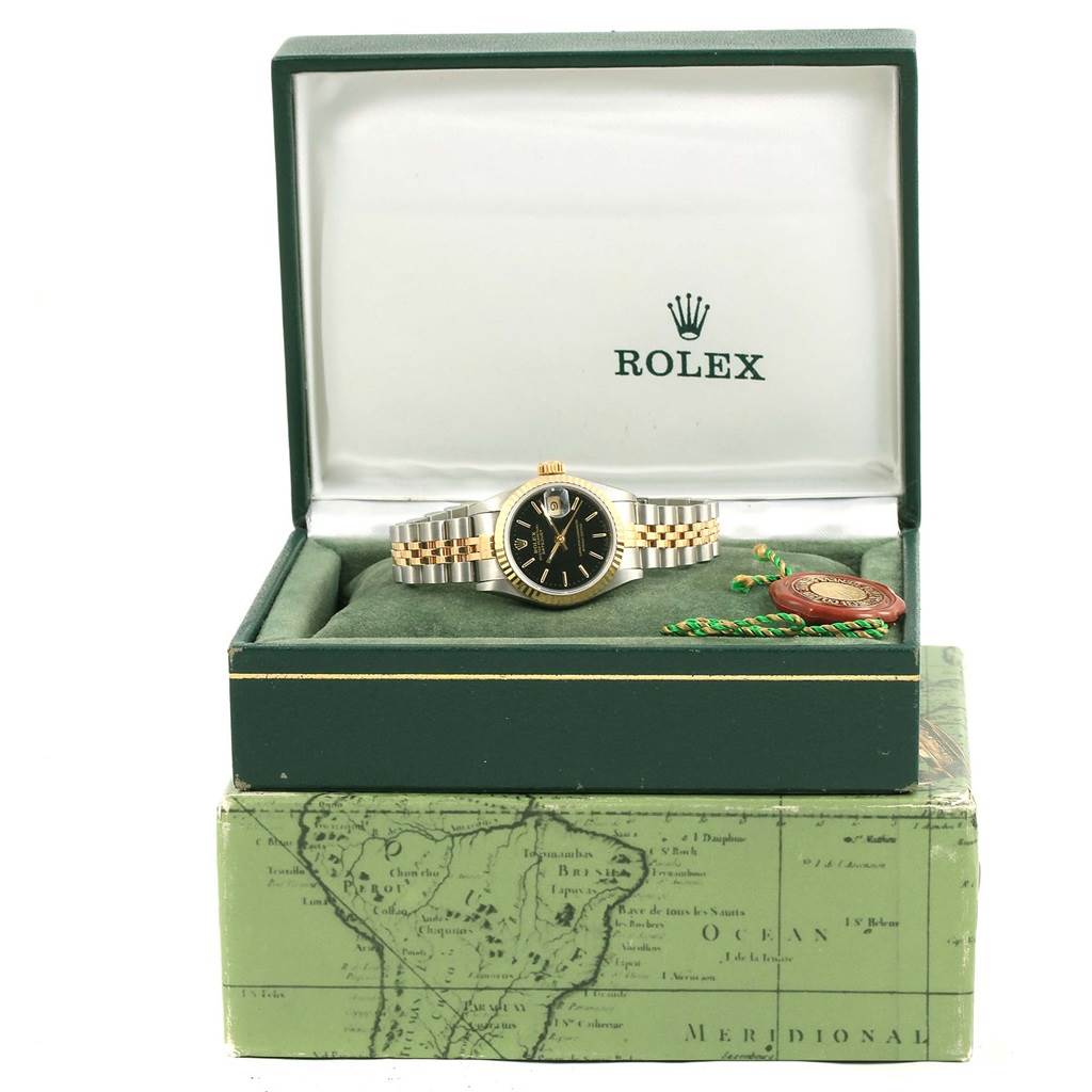 The Rolex Datejust 69173 Women's Stainless Steel Black Dial 69173 Women's Stainless Steel Black Dial watch is photographed from the front inside its open green box, showing the face, bracelet, and accompanying accessories.