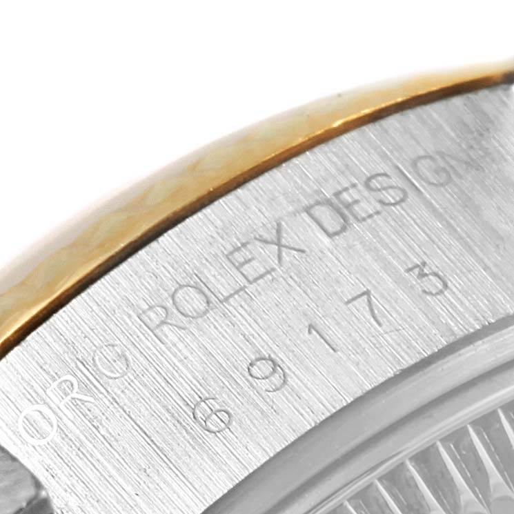 This close-up image of a Rolex Datejust 69173 Women's Stainless Steel Champagne Dial 69173 Women's Stainless Steel Champagne Dial watch shows part of the bezel and engraved serial numbers.