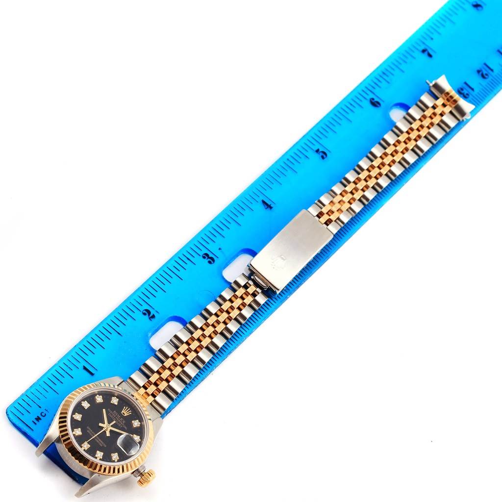 The image shows a Rolex Datejust 69173 Women's Stainless Steel Black Dial 69173 Women's Stainless Steel Black Dial watch laid flat on a ruler, highlighting the watch's face, bezel, crown, and bracelet.