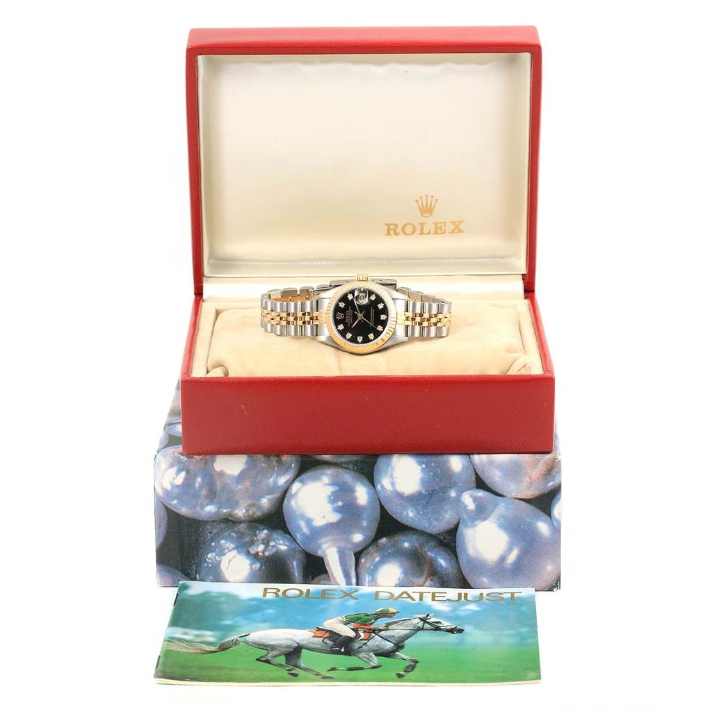 The Rolex Datejust 69173 Women's Stainless Steel Black Dial 69173 Women's Stainless Steel Black Dial watch is shown from the front, inside its open box with an accompanying booklet displayed beneath.