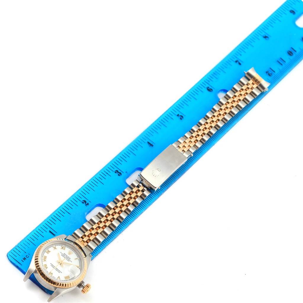 The Rolex Datejust 79173 Women's Steel and Gold (two tone) White Dial 79173 Women's Steel and Gold (two tone) White Dial watch is shown from the top view, featuring its dial, case, and Jubilee bracelet alongside a blue ruler.