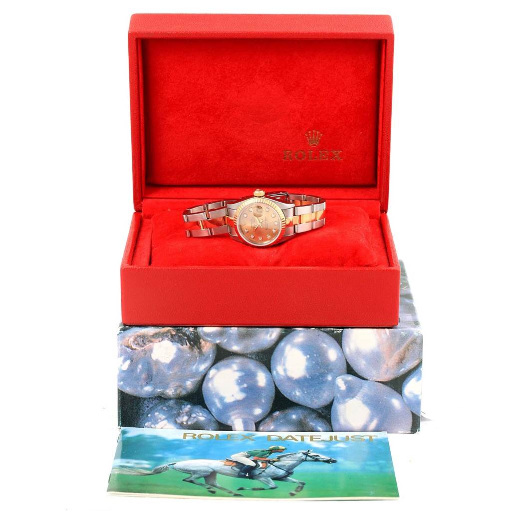 The Rolex Datejust 69173 Women's Stainless Steel Champagne Dial 69173 Women's Stainless Steel Champagne Dial watch is displayed front-facing in an open red box, with its bracelet and dial visible, alongside a brochure.