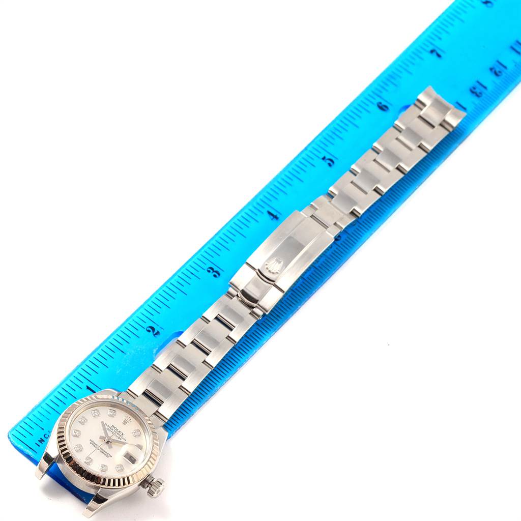 The image shows a Rolex Datejust 179174 Women
s Stainless Steel Mother of Pearl Dial 179174 Women
s Stainless Steel Mother of Pearl Dial watch laid flat next to a blue ruler, highlighting the dial and bracelet.