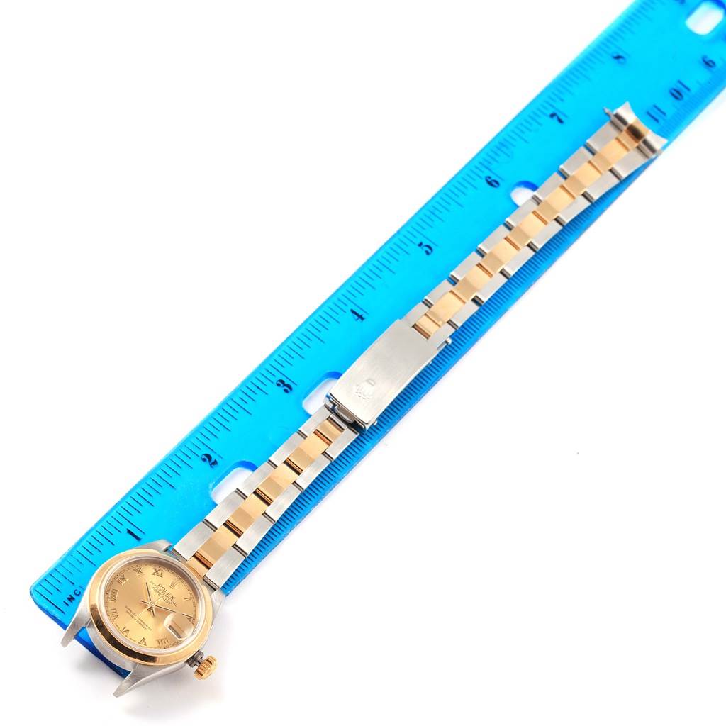 The image shows a Rolex Datejust 79163 Women's Steel and Gold (two tone) Champagne Dial 79163 Women's Steel and Gold (two tone) Champagne Dial watch laid flat alongside a blue ruler, displaying its dial and bracelet clearly.