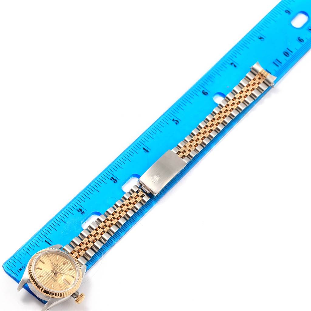 The image shows a Rolex Datejust 69173 Women's Stainless Steel Champagne Dial 69173 Women's Stainless Steel Champagne Dial watch face and bracelet next to a blue ruler, viewed from above.