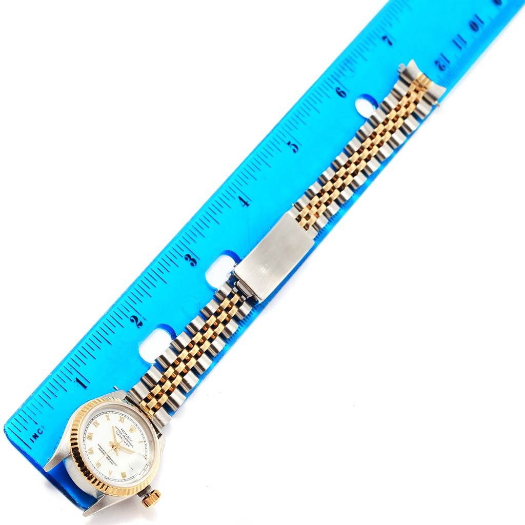 This image shows a Rolex Datejust 69173 Women's Stainless Steel White Dial 69173 Women's Stainless Steel White Dial watch horizontally placed next to a blue ruler, highlighting its face, bezel, bracelet, and clasp.