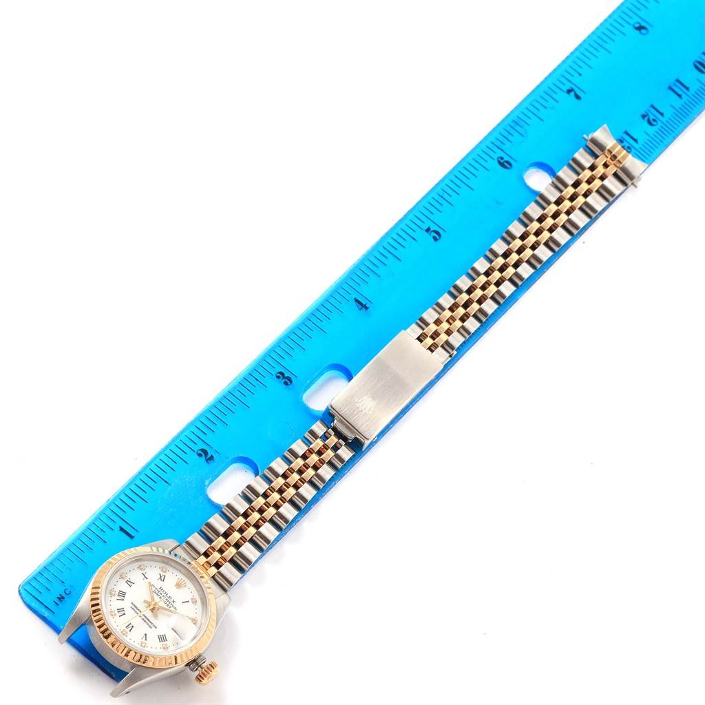 The image shows a Rolex Datejust 69173 Women's Stainless Steel White Dial 69173 Women's Stainless Steel White Dial watch face and its two-tone bracelet laid next to a blue ruler for measurement.