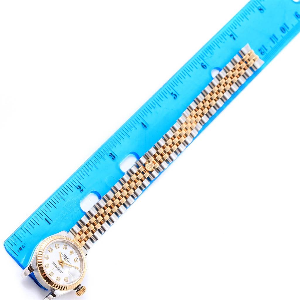The Rolex Datejust 179173 Women's Steel and Gold (two tone) White Dial 179173 Women's Steel and Gold (two tone) White Dial watch is shown face-up next to a blue ruler, displaying its dial and bracelet.