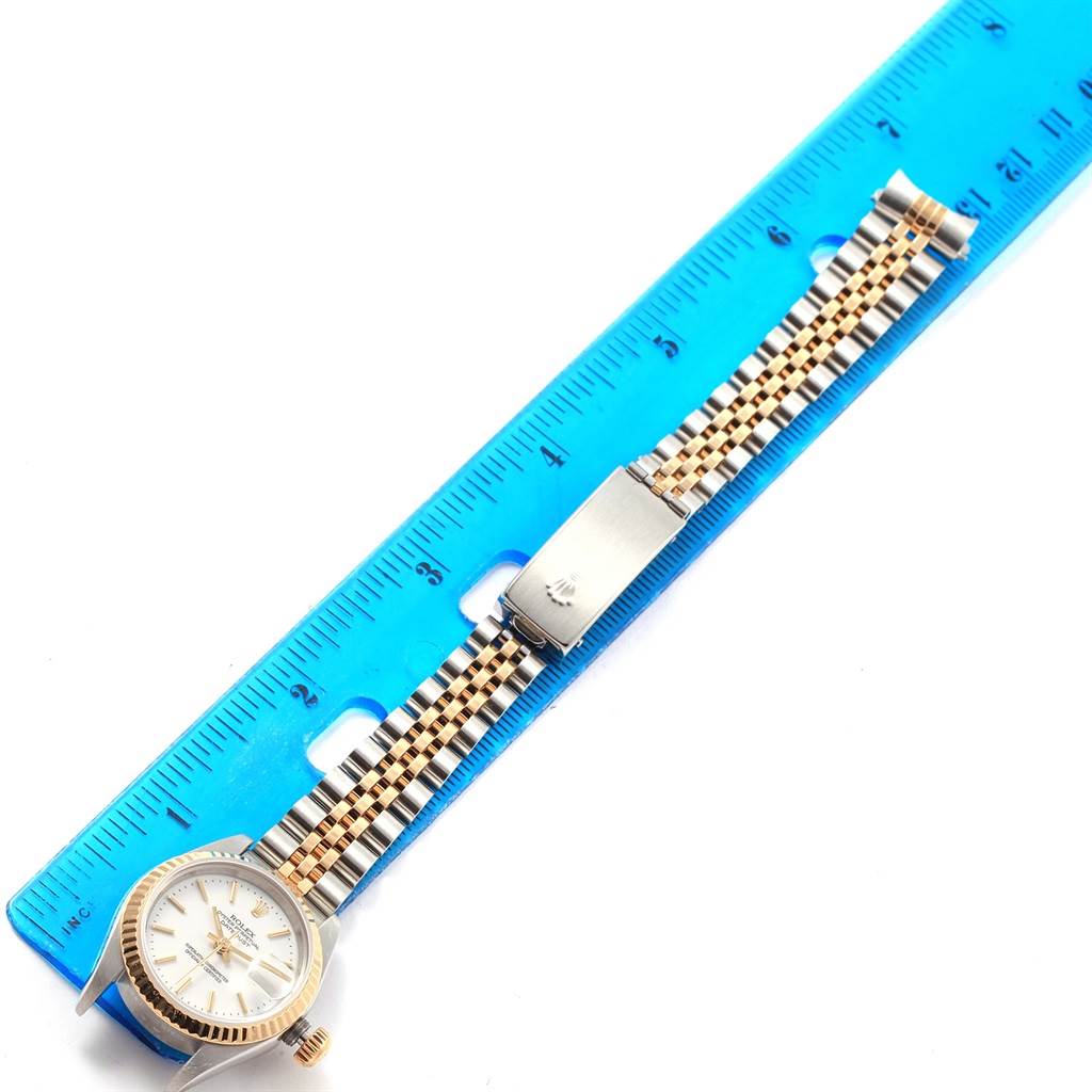 This image shows a Rolex Datejust 79173 Women's Steel and Gold (two tone) White Dial 79173 Women's Steel and Gold (two tone) White Dial watch laid flat next to a ruler, displaying the face, bracelet, and clasp.