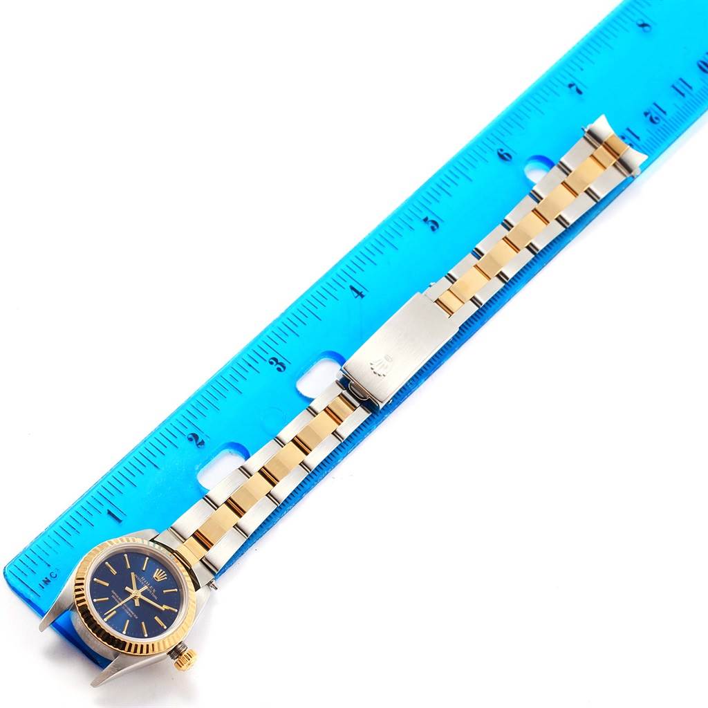 The image shows a top-down view of a Rolex Datejust 76193 Women's Steel and Gold (two tone) Blue Dial 76193 Women's Steel and Gold (two tone) Blue Dial watch placed next to a blue ruler for scale.