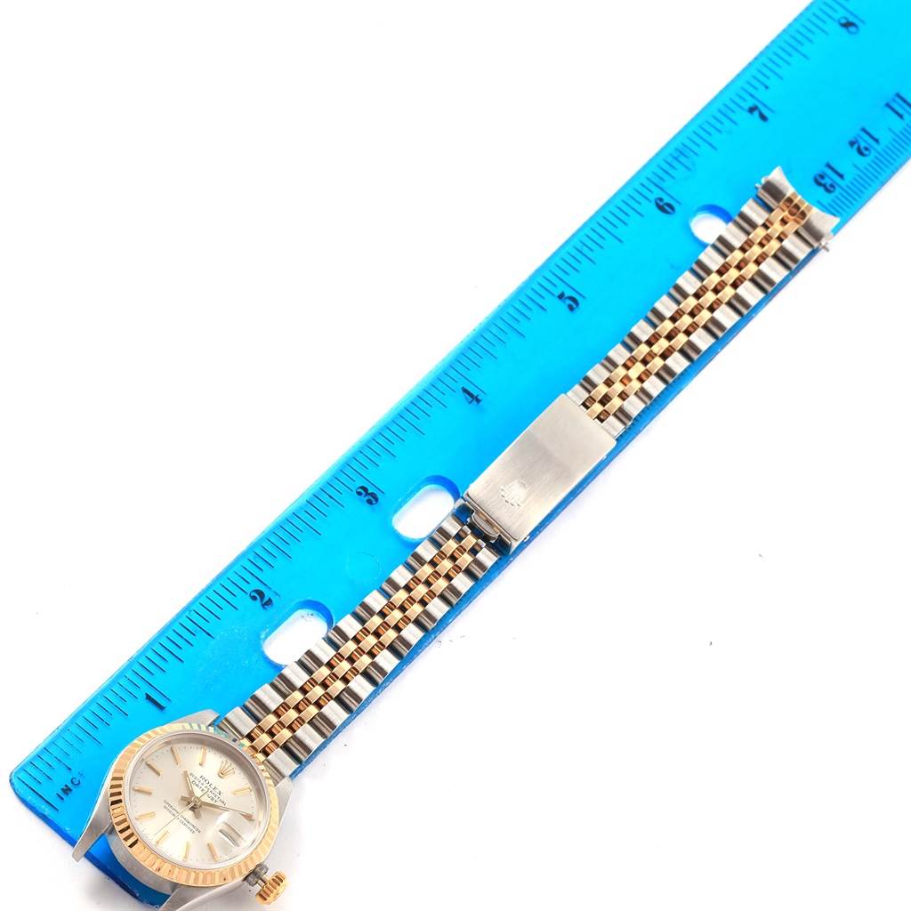 The Rolex Datejust 69173 Women's Stainless Steel Silver Dial 69173 Women's Stainless Steel Silver Dial watch is shown from the front, including the face, bezel, and bracelet, placed next to a blue ruler for scale.