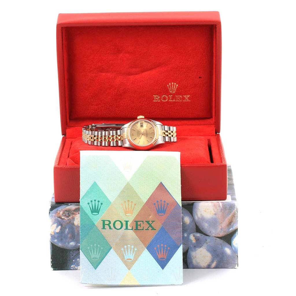 The Rolex Datejust 79173 Women's Steel and Gold (two tone) Champagne Dial 79173 Women's Steel and Gold (two tone) Champagne Dial watch is shown in its open red box with accompanying documents in front.