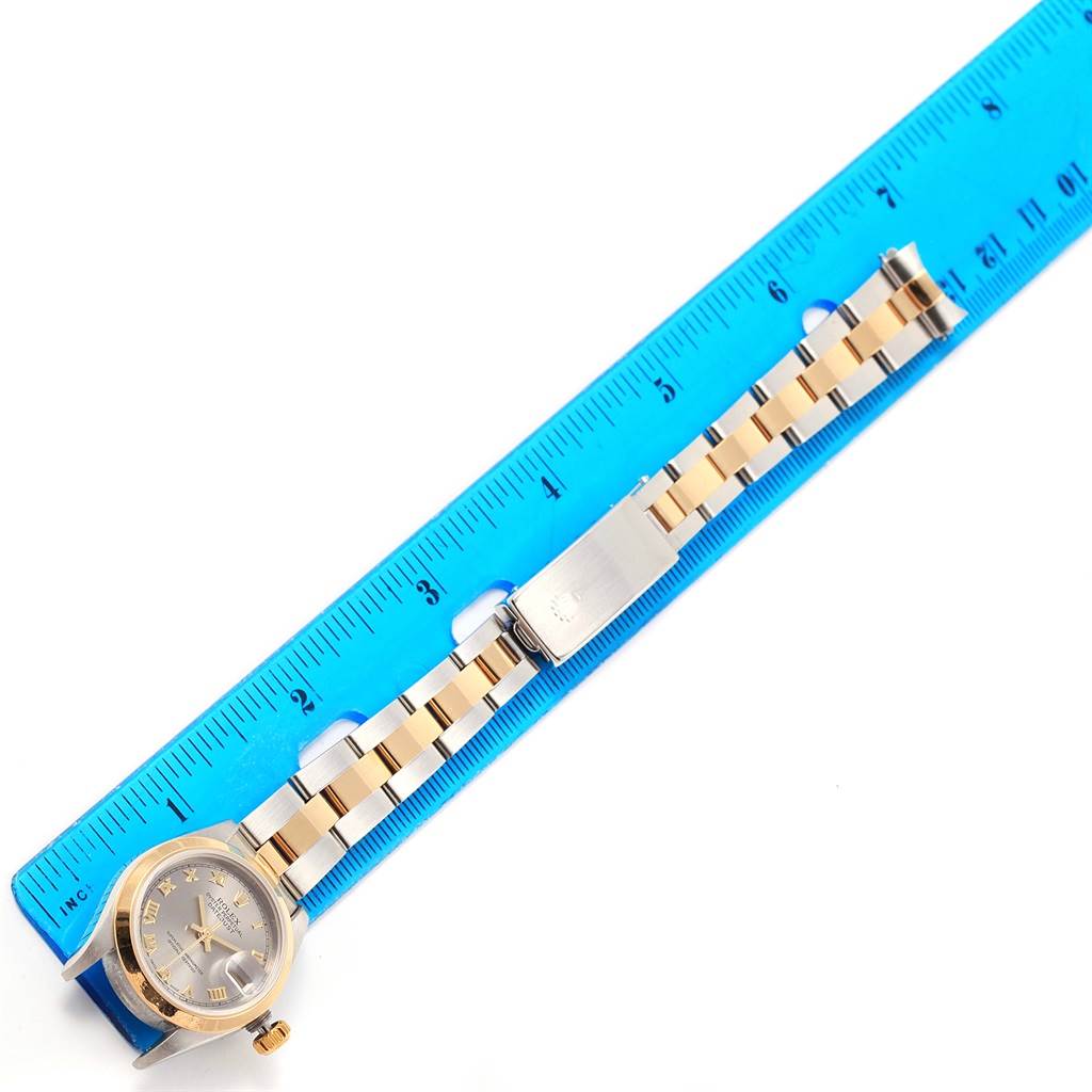 The Rolex Datejust 69163 Women's Stainless Steel Grey Dial 69163 Women's Stainless Steel Grey Dial model watch is shown from above, with the face and band, alongside a blue ruler for scale.