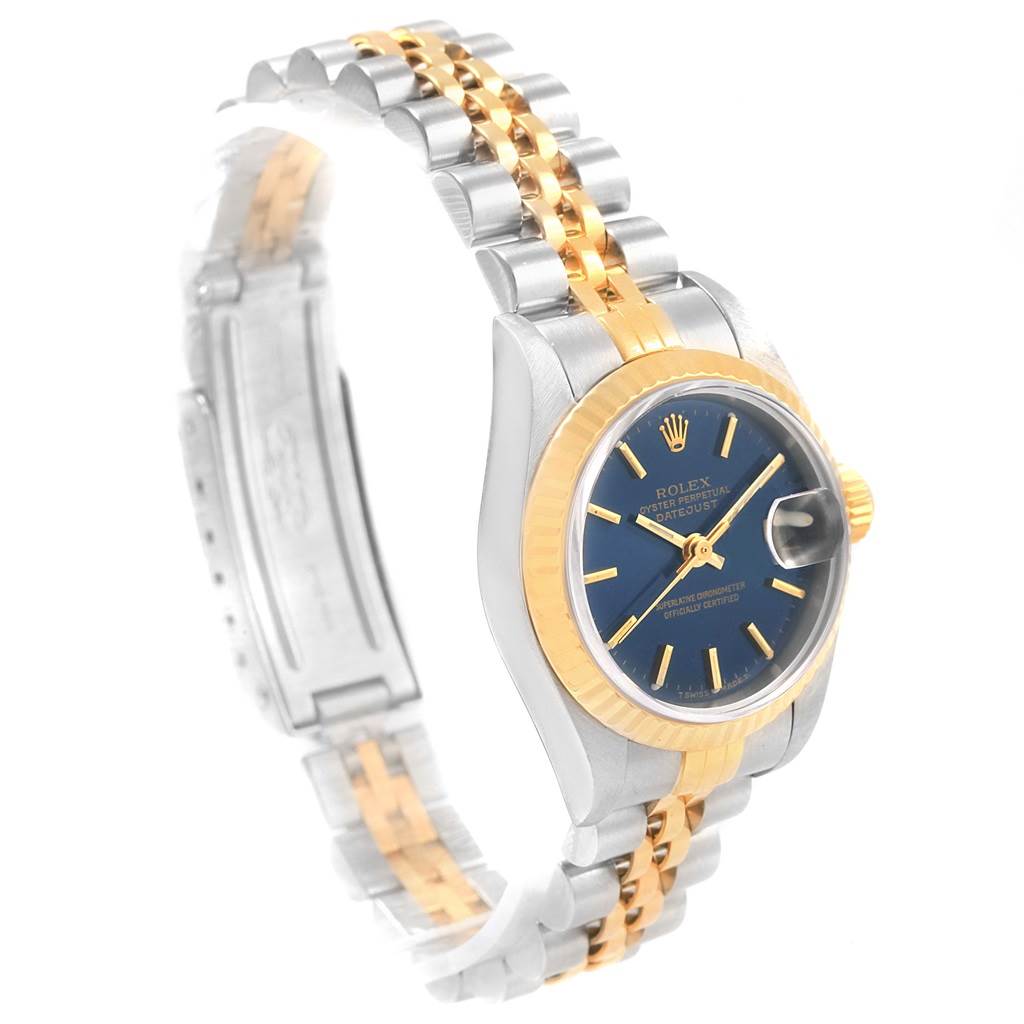 The image shows a Rolex Datejust 79173 Women's Steel and Gold (two tone) Blue Dial 79173 Women's Steel and Gold (two tone) Blue Dial watch at an oblique angle, displaying its blue dial, gold fluted bezel, and two-tone bracelet.