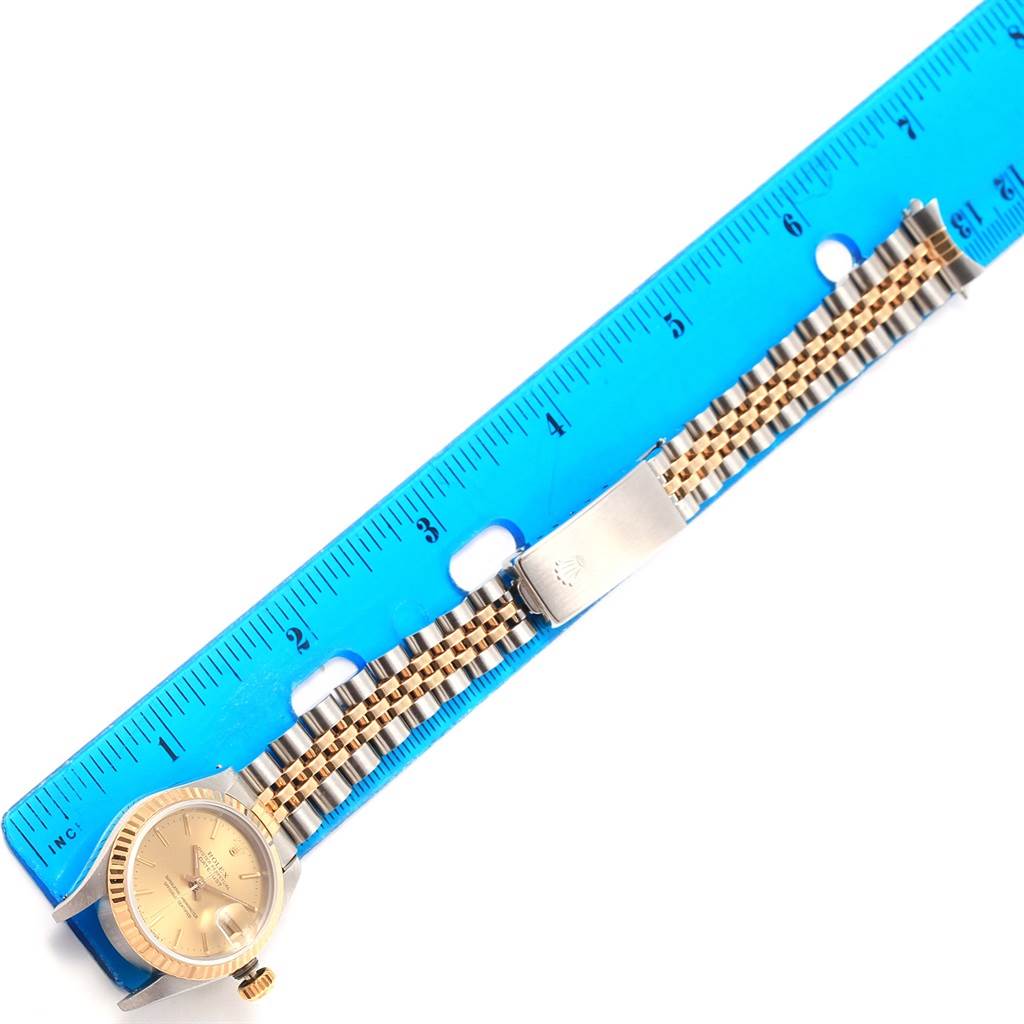 A Rolex Datejust 69173 Women's Stainless Steel Champagne Dial 69173 Women's Stainless Steel Champagne Dial watch is shown from an overhead angle, featuring the face, bezel, bracelet, and part of a clasp against a ruler for scale.