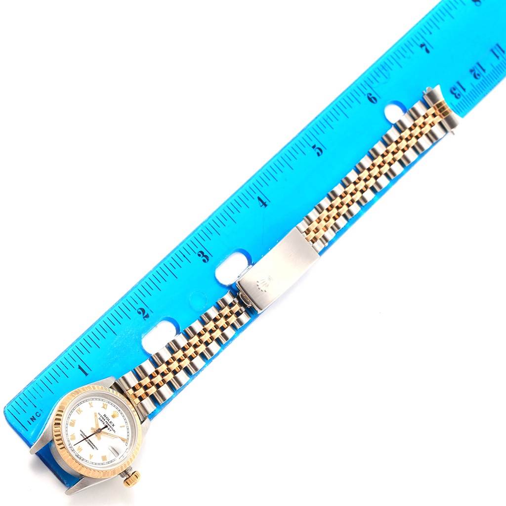 The image shows a Rolex Datejust 69173 Women's Stainless Steel White Dial 69173 Women's Stainless Steel White Dial watch laid flat next to a ruler, highlighting its face, bezel, and metal band.